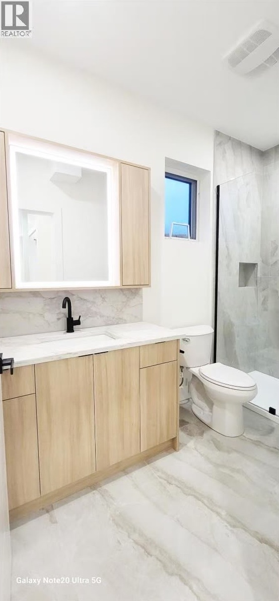 Bathroom with oak vanity, backlit mirror cabinet and marble-look tile