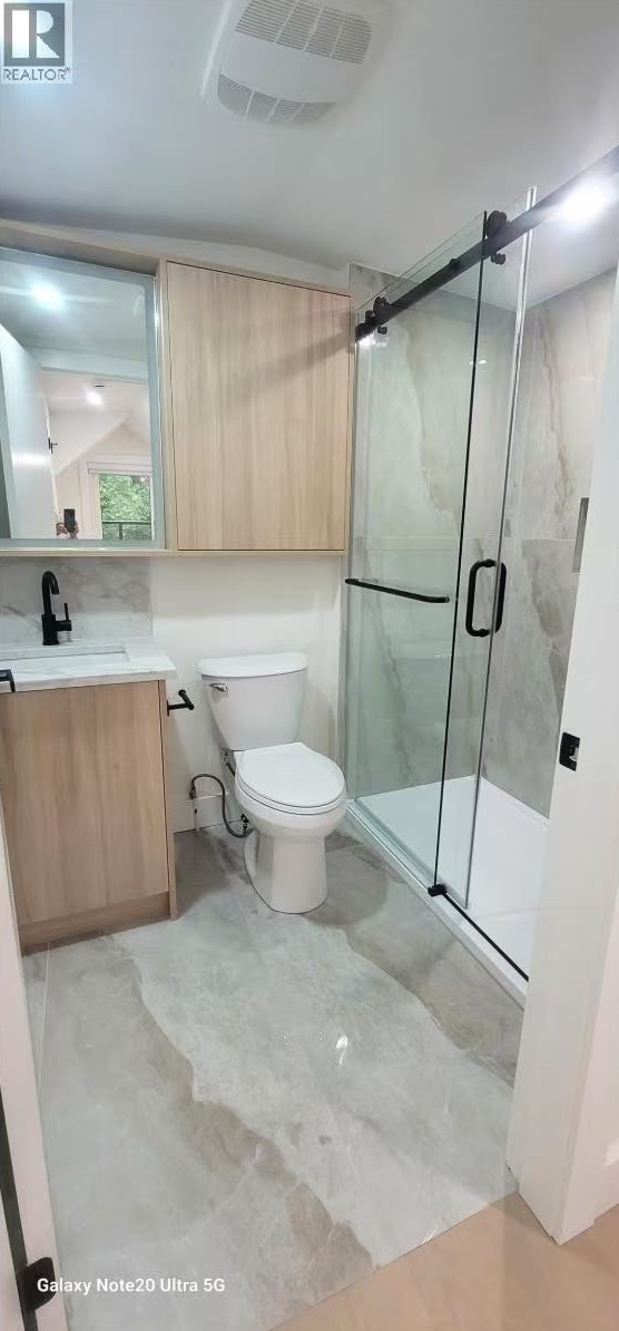 Bathroom with sliding glass shower door and oak cabinetry